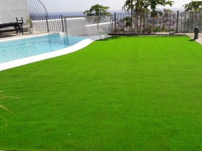 Piscina con césped artificial en jardín