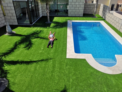 piscina con césped artificial en jardín
